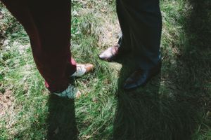 two partners feet in green mossy grass with their wedding shoes on