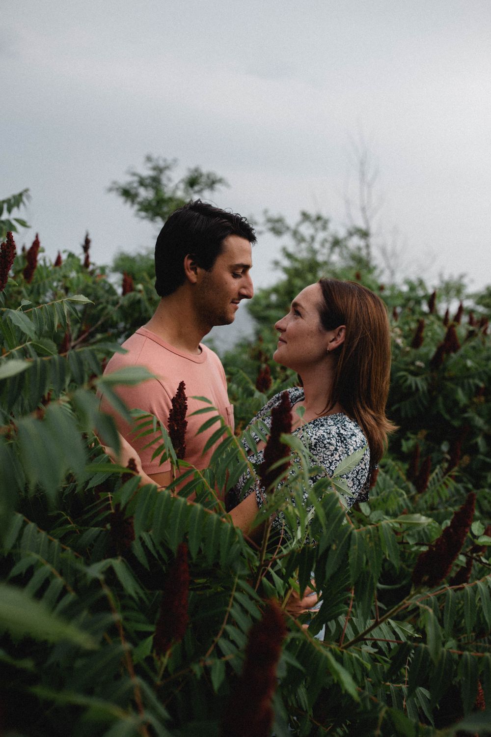 white hetero couple engaged standing and gazing at each other in New England foliage on beach