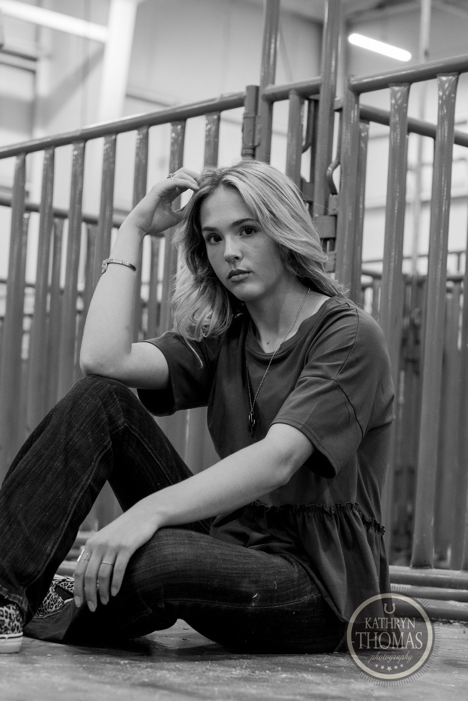 Black and white portrait in industrial setting shows dramatic lighting and casual style.