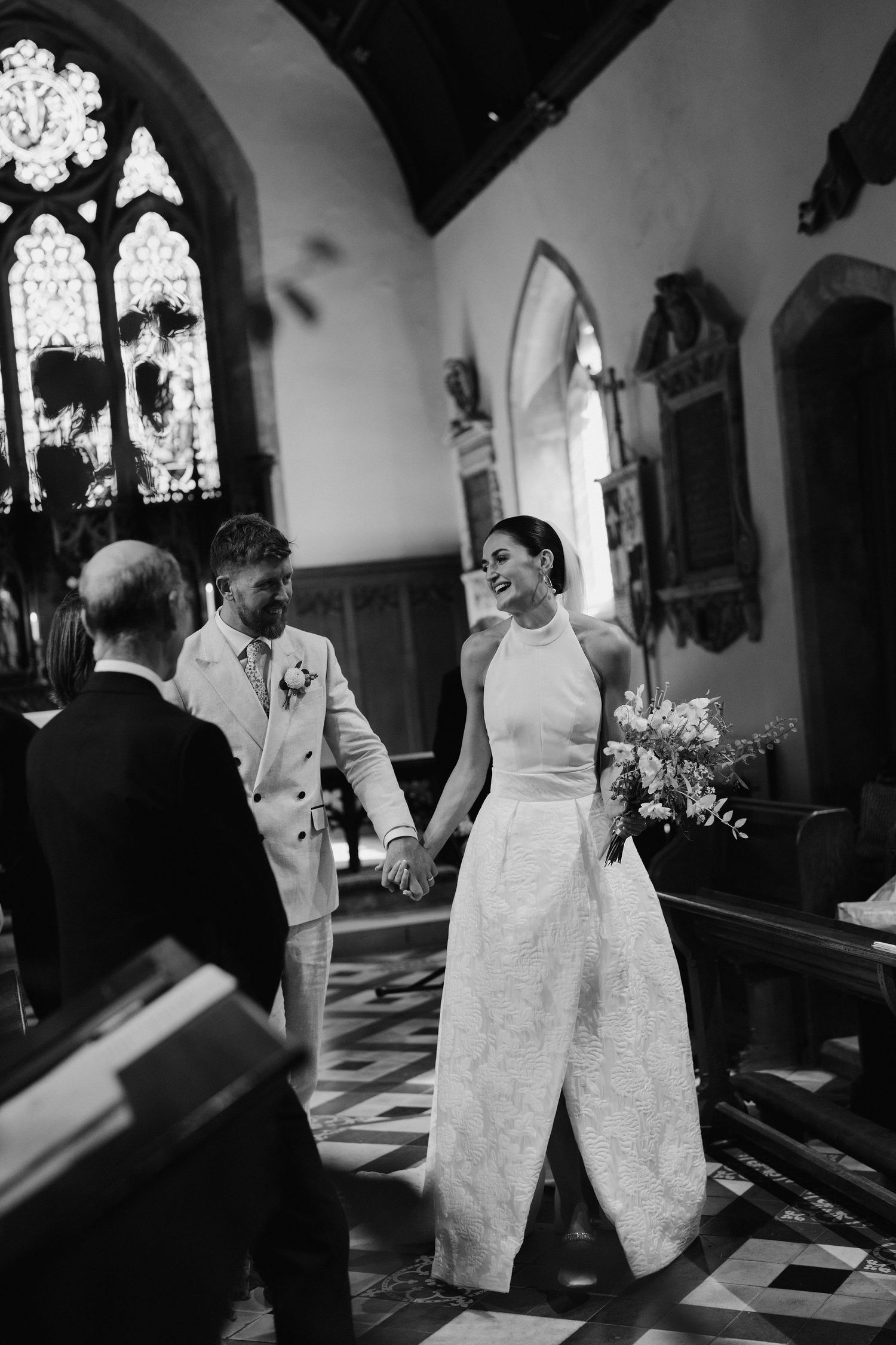bride and groom laughing with each other as they start to come down the aisle as husband and wife at st Nicholas church in Oxfordshire