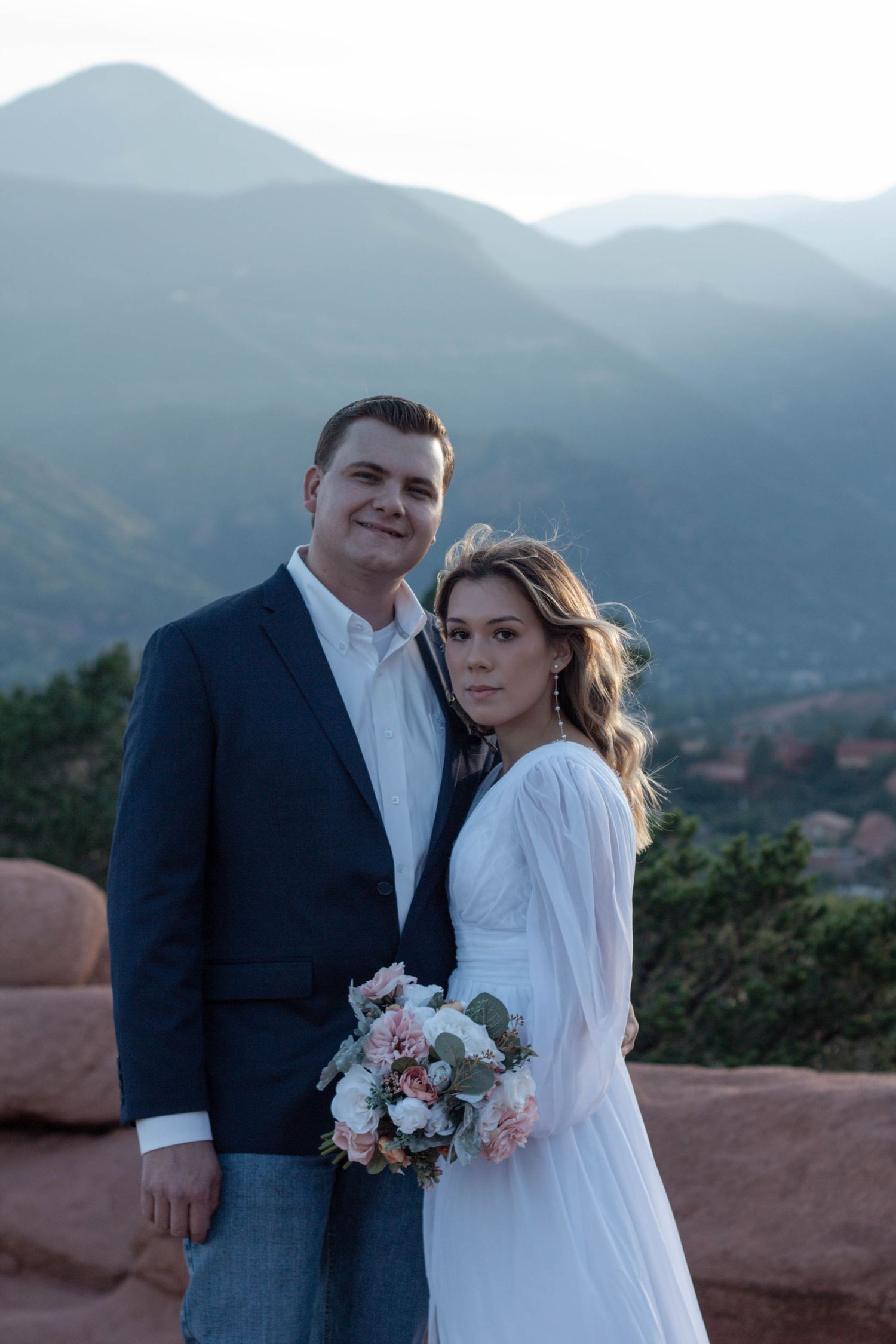 A couple in wedding attire poses against scenic mountain backdrop at Garden of the Gods during sunset. Elopement photographer