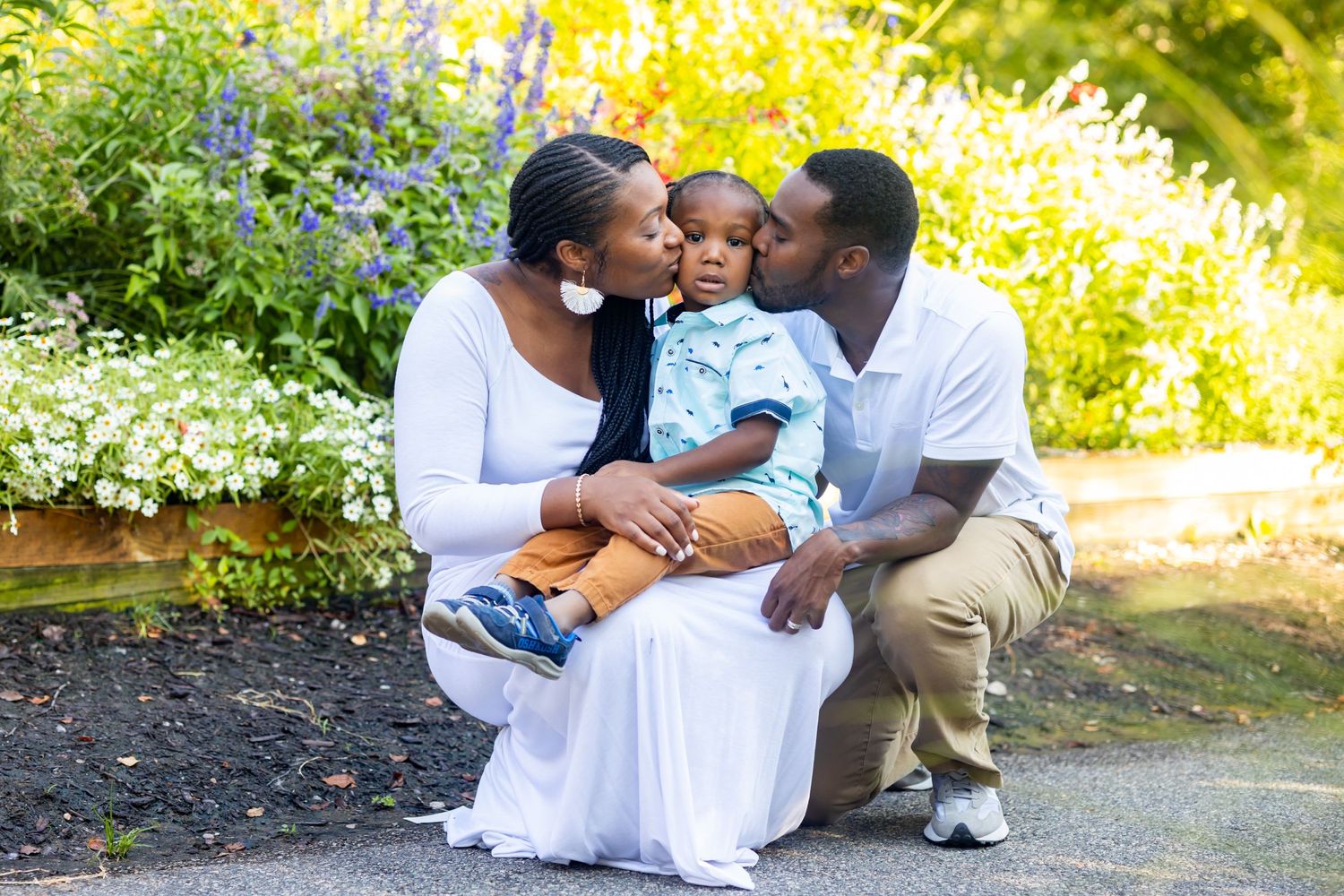 Family shares intimate moment together on garden bench during outdoor photo session.