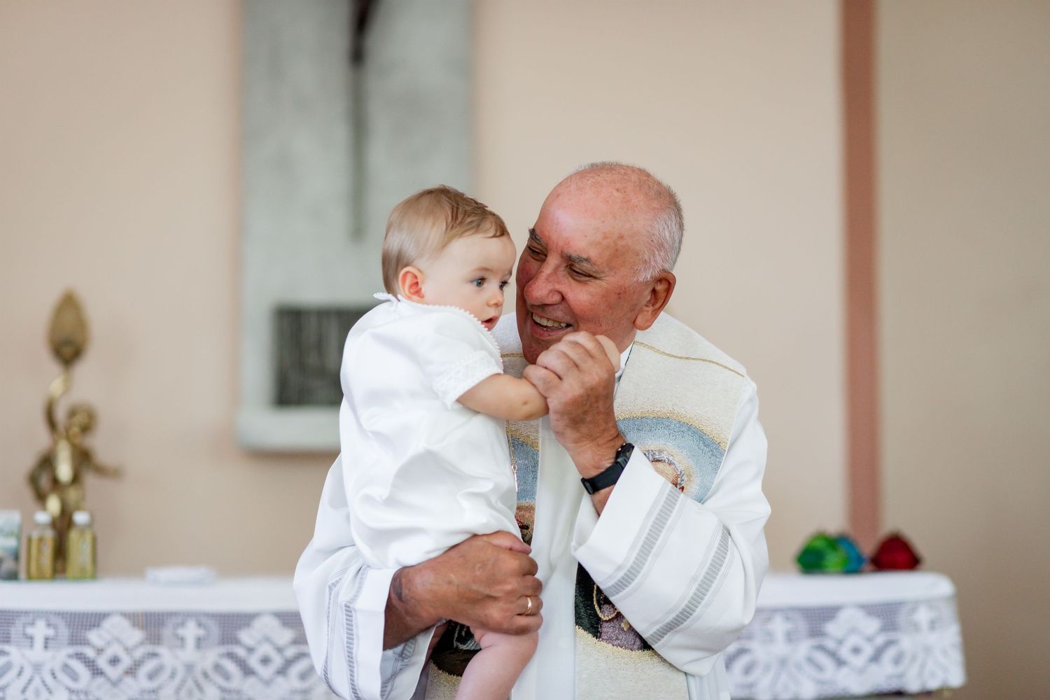 Tender moment during religious ceremony at church altar with white decorations.