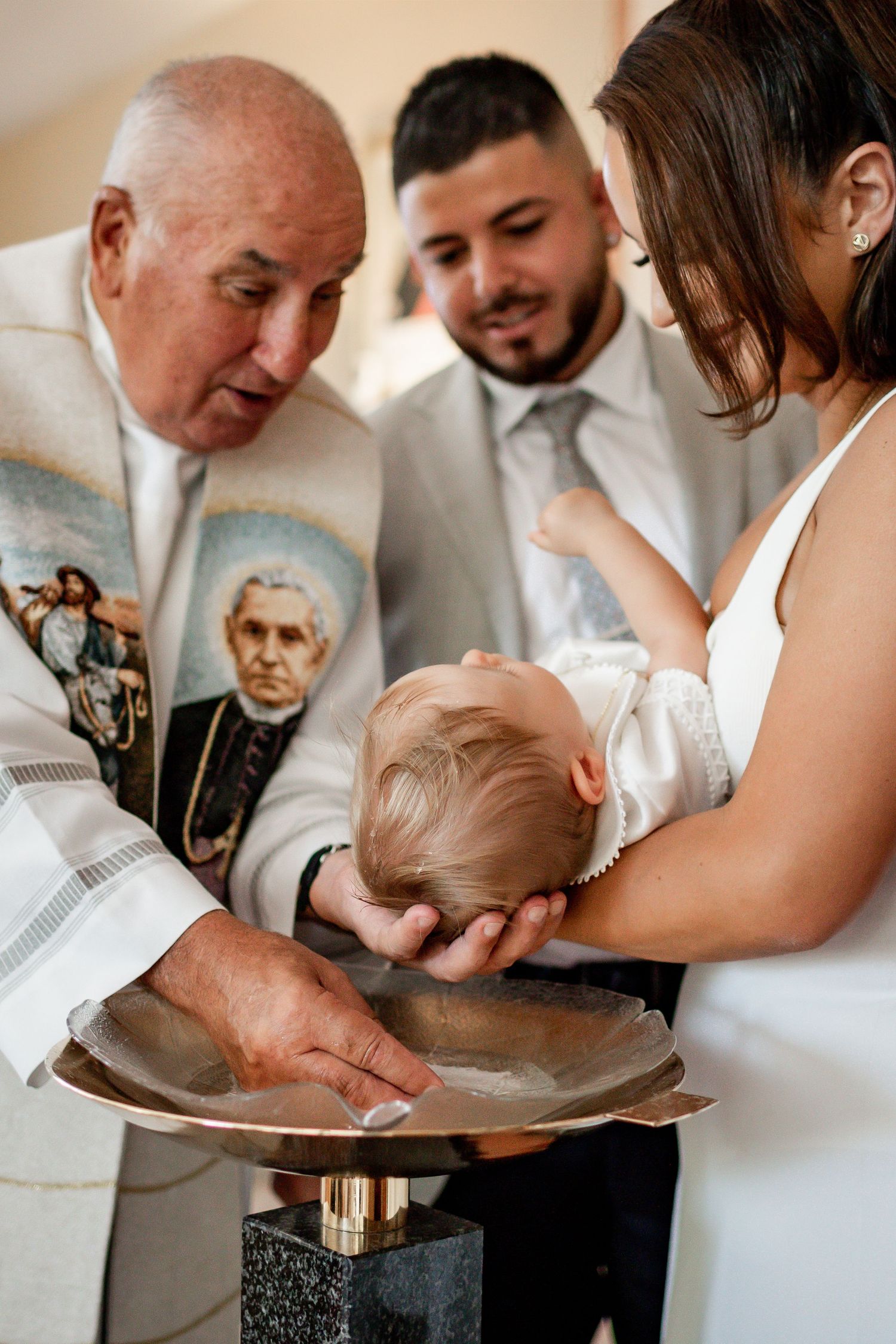 Close-up shot of baptismal blessing with holy water and religious imagery in background.