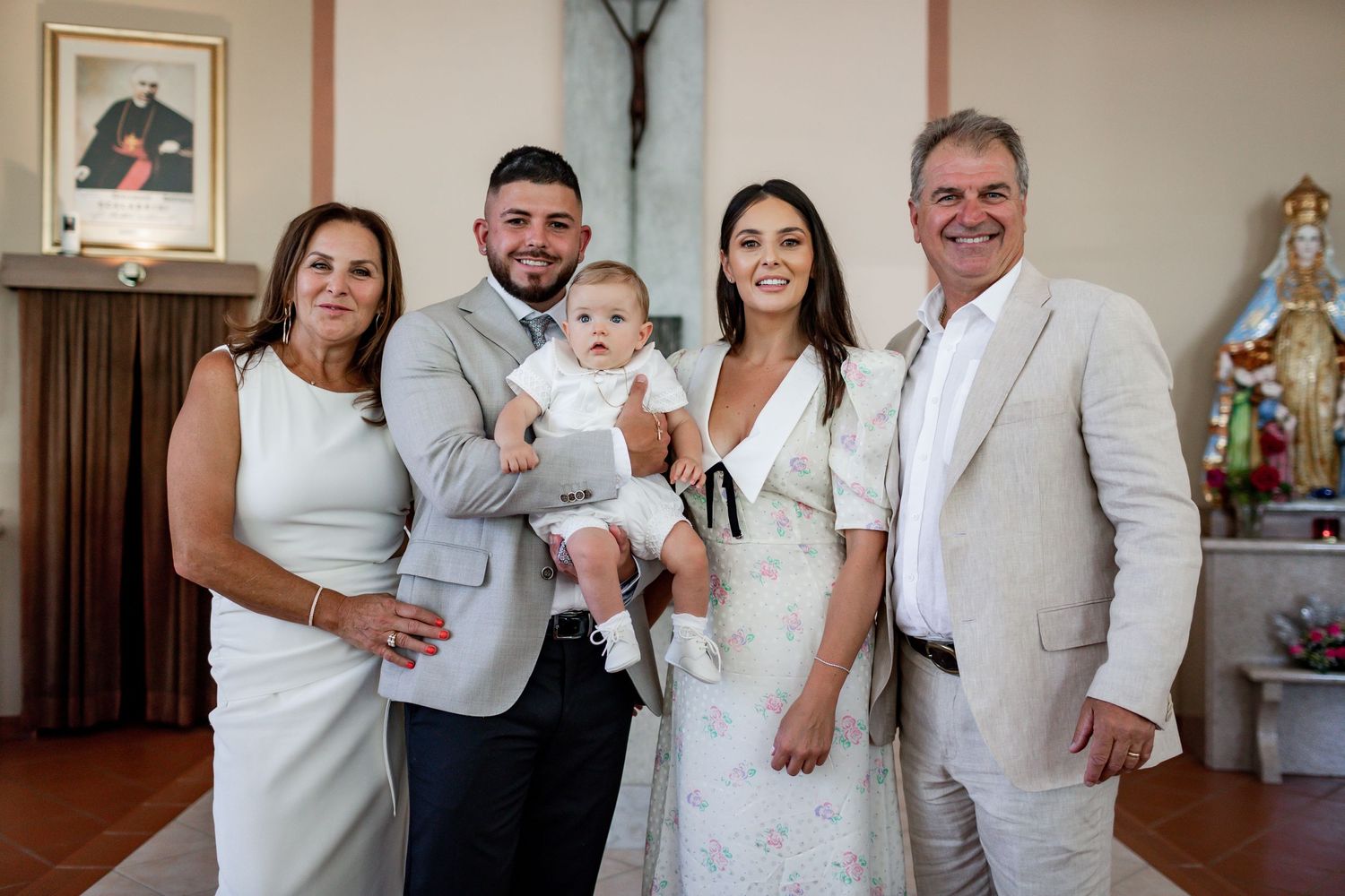 A group wearing coordinated white and beige outfits pose together in a church interior.