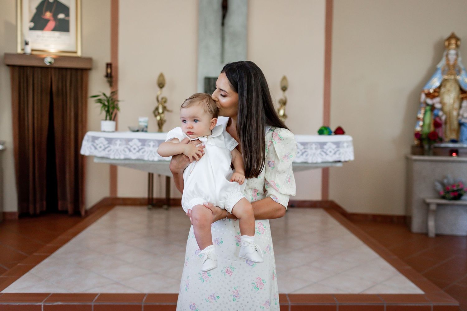 A sweet moment captured in white formal wear at a church christening ceremony.