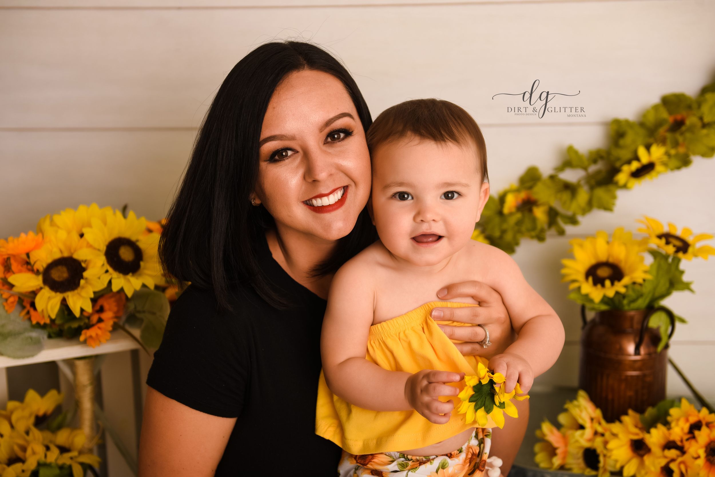mom smiling with baby in front of sunflowers