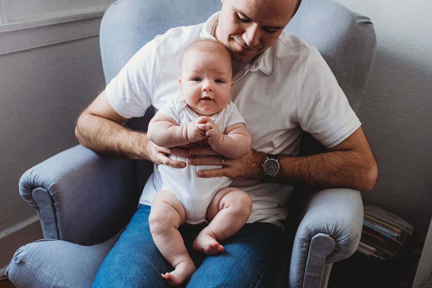 An intimate family portrait shows a tender moment in a cozy armchair.