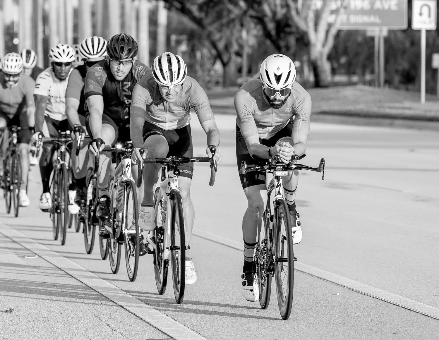 Group of cyclists riding in formation on urban street during daytime event.