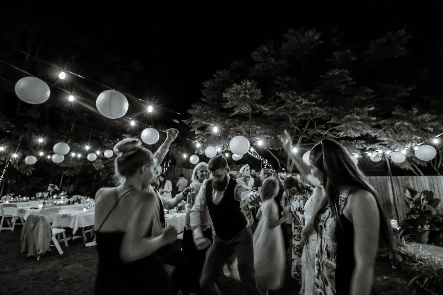 Black and white photo of a nighttime outdoor celebration with lanterns and dancing.