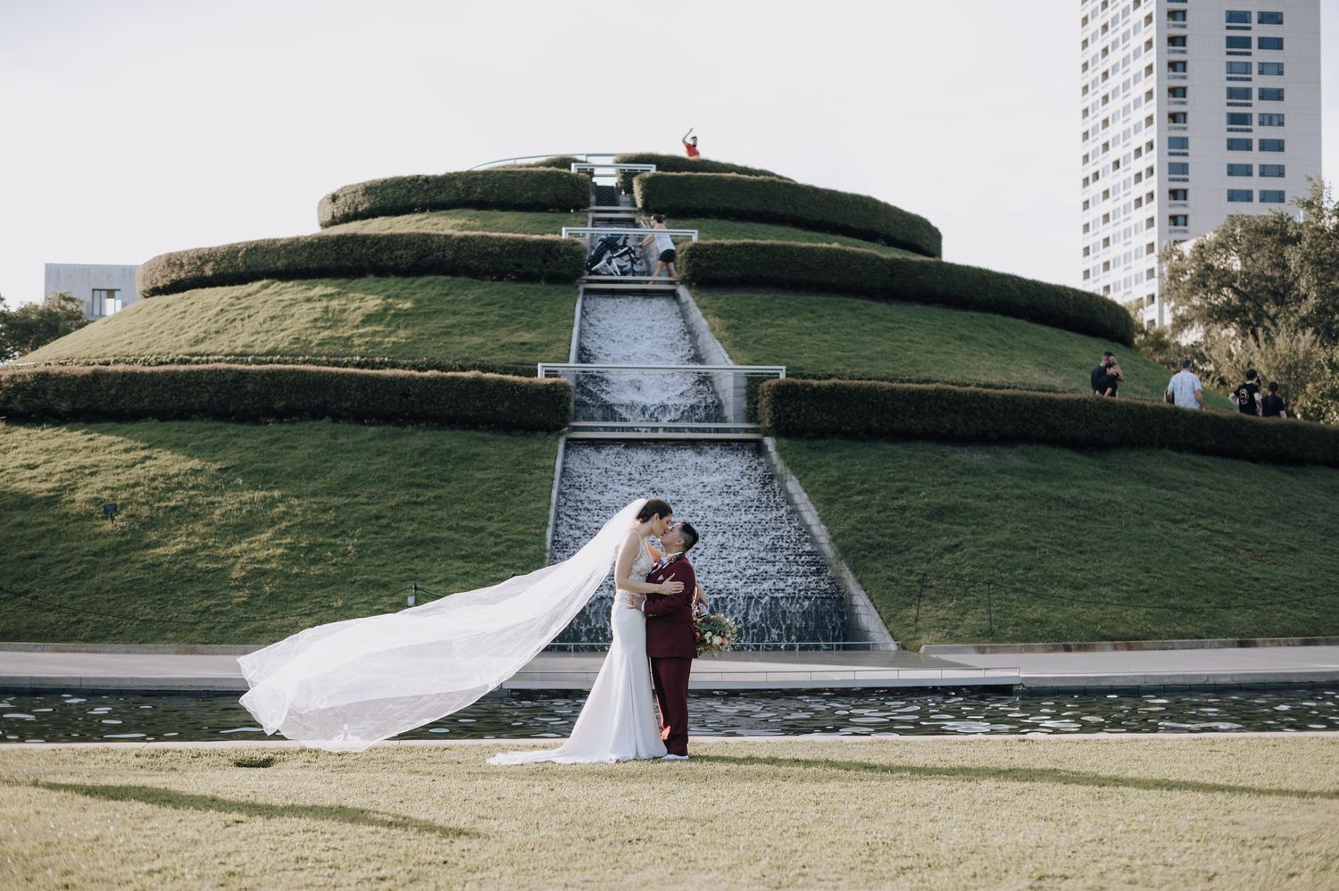 Wedding couple photographed at circular grass amphitheater with dramatic veil movement.