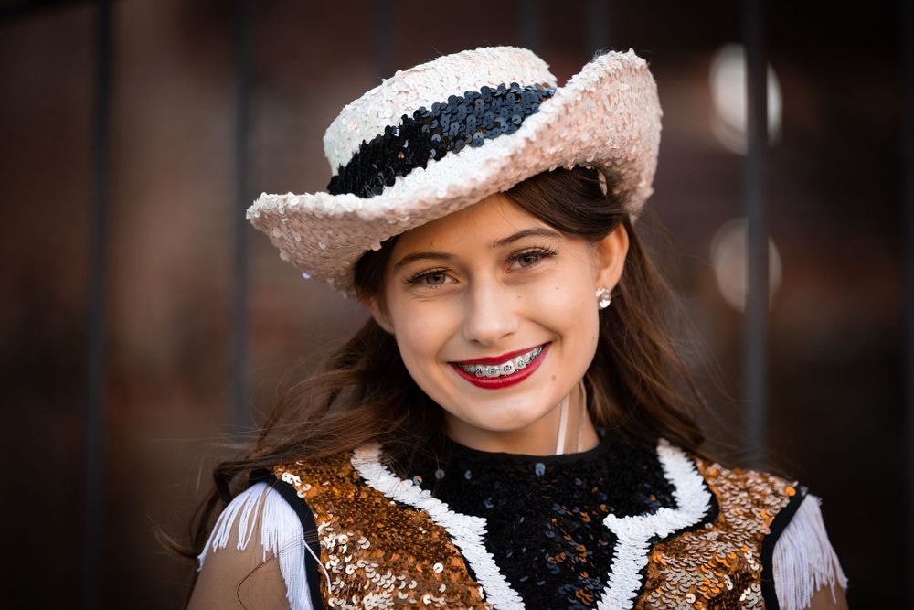 Performer wearing ornate western costume and decorative hat smiles at camera.