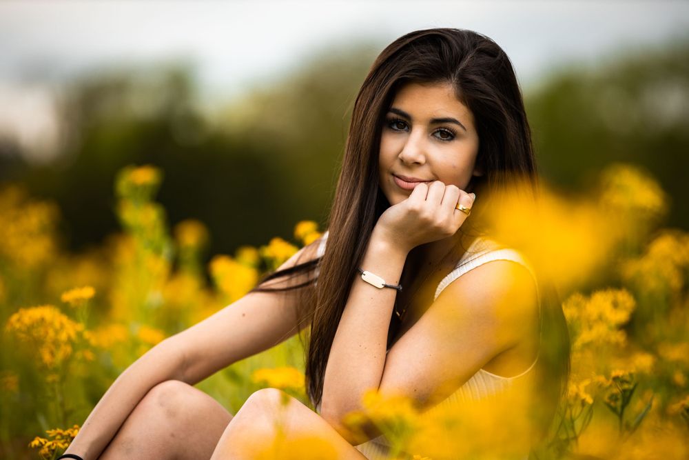 A summer portrait among yellow wildflowers with soft natural lighting.