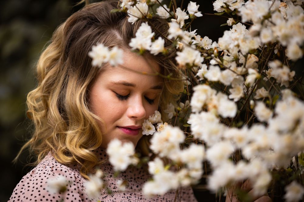 Delicate white cherry blossoms frame a soft, romantic portrait in springtime.