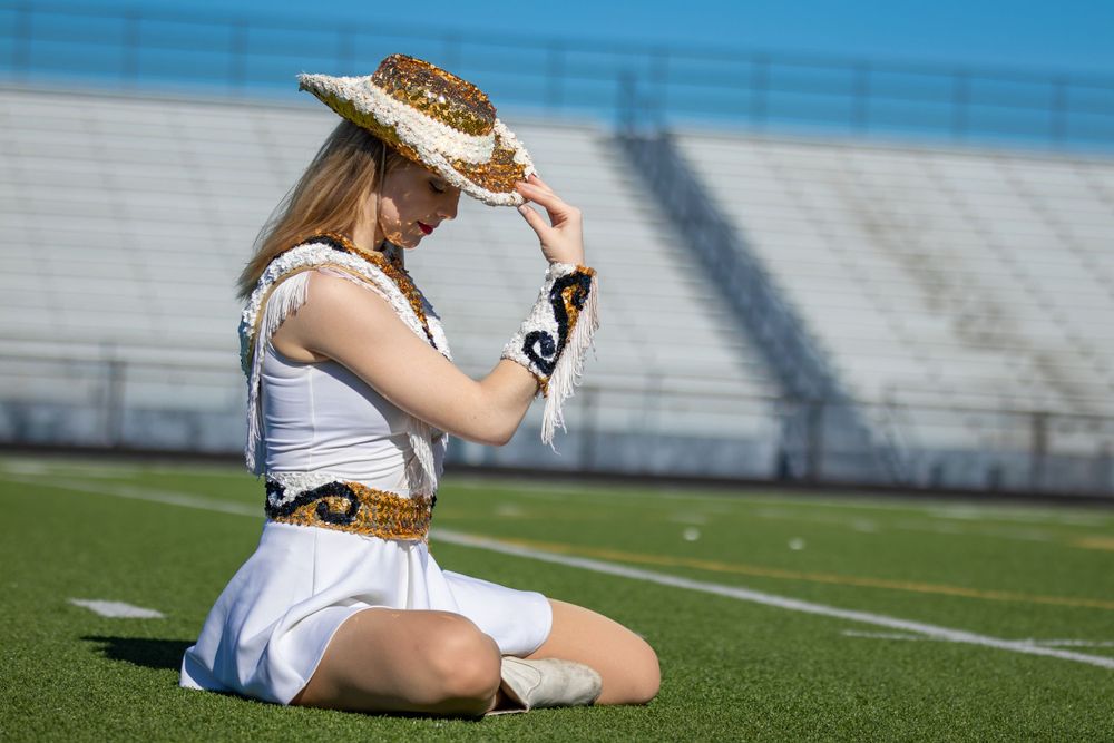A western-styled portrait on sports field turf with stadium seating in background.
