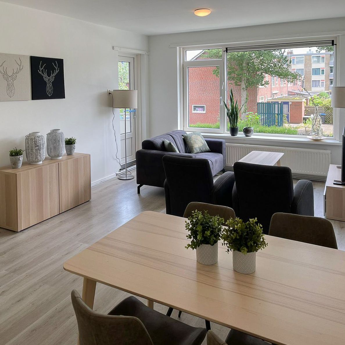 Living room furnished with a gray sofa, gray arm chairs and basic furniture in light wood color