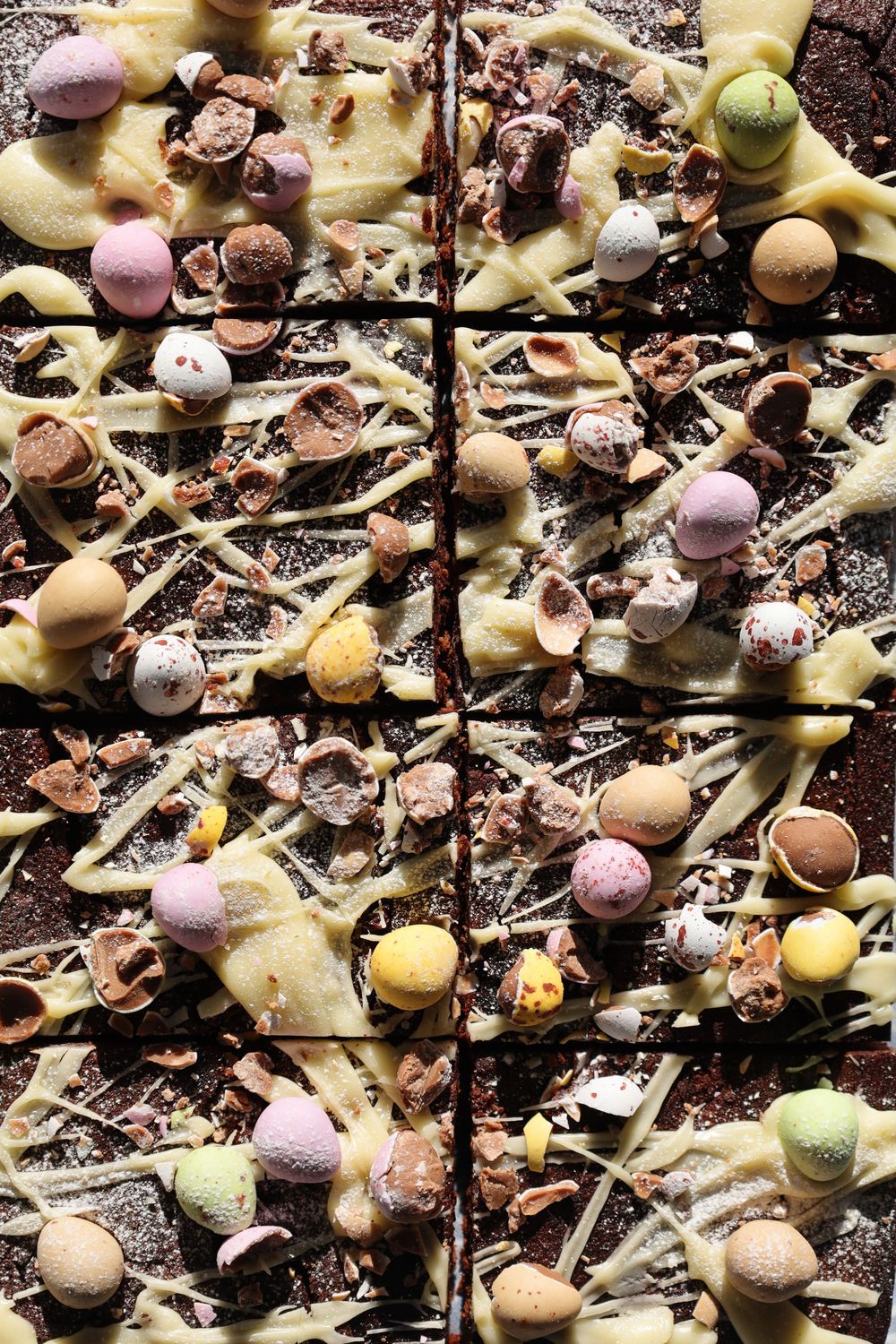 Colorful miniature Easter eggs scattered on a dark textured background.