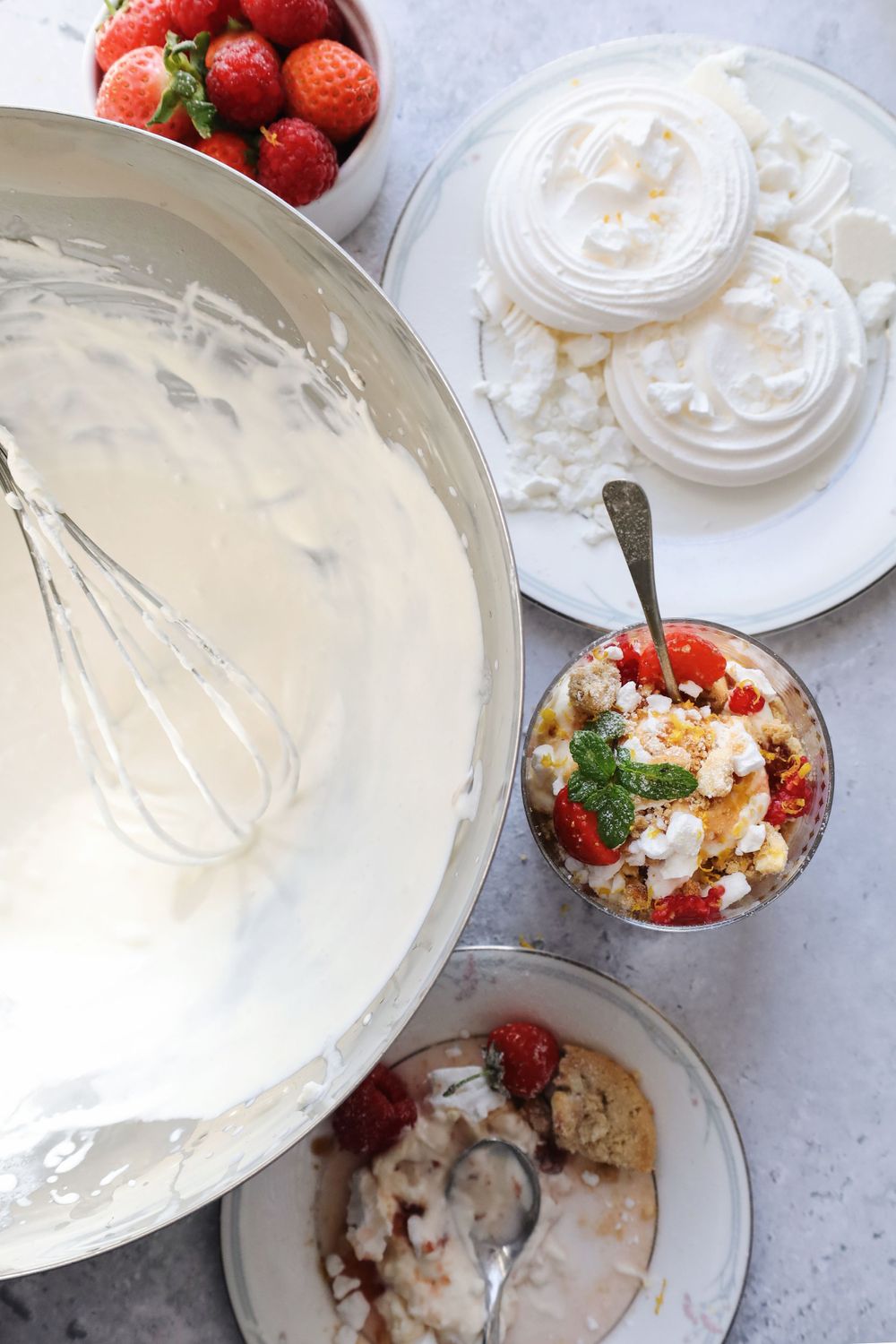 Fresh strawberries and whipped cream are arranged in elegant glass dessert bowls.