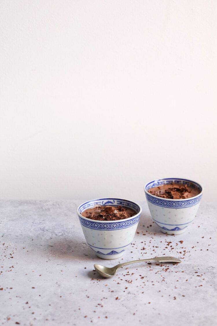 Two blue and white Chinese porcelain bowls containing dessert on a light surface.