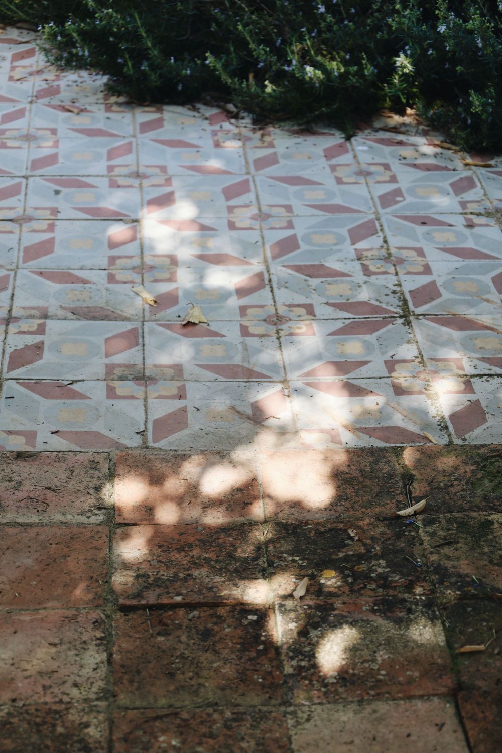 Dappled sunlight creates geometric patterns on a textured stone wall surface.