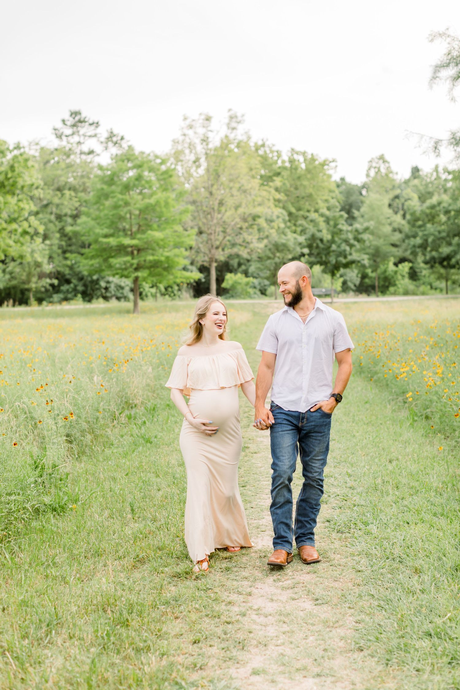 A couple walks hand in hand along a nature path during their springtime maternity photo session.