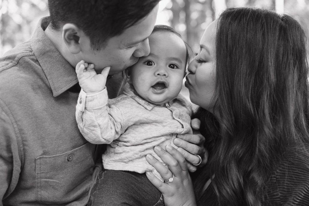 A sweet black and white family moment with parents sharing affection with their baby.