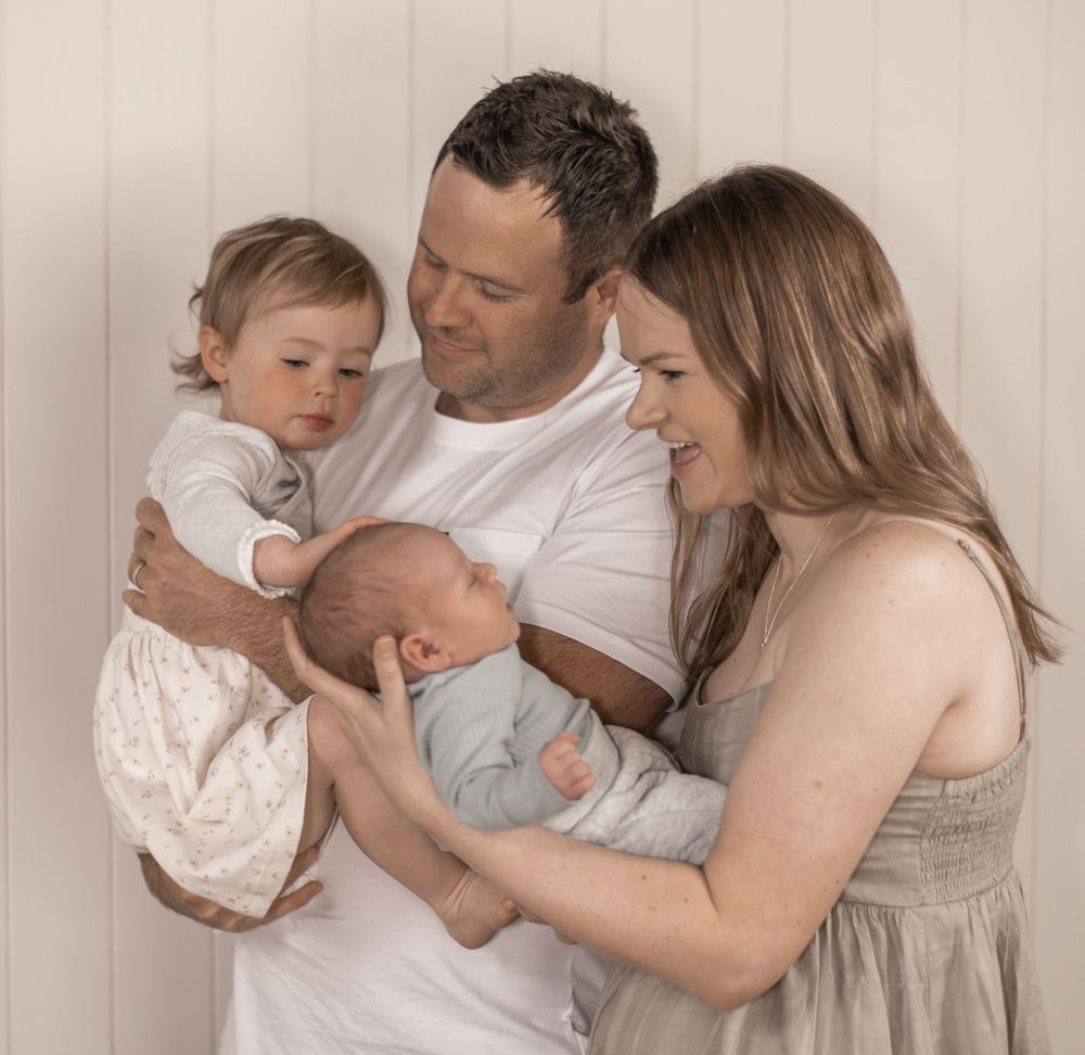 Gentle family portrait series in soft beige tones showing tender moments between parents and baby.