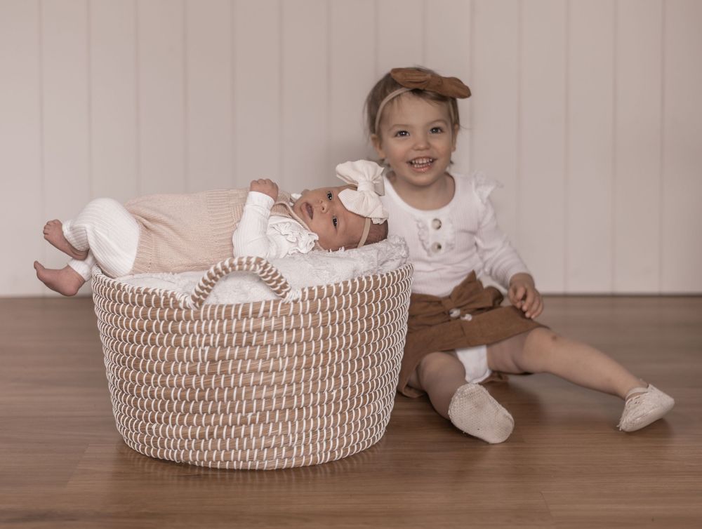 A series of photos showing a baby in white baptismal attire positioned in a woven basket on wooden flooring.