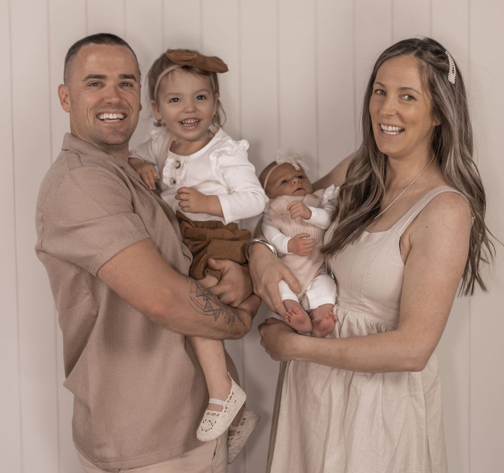 Family in coordinated beige outfits posing together for portrait session.