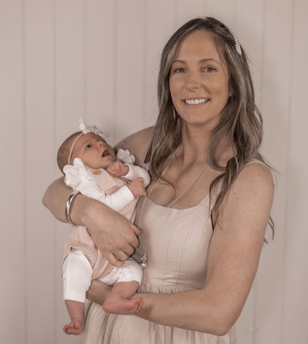 Woman in beige dress holds baby in white outfit in three similar poses against light colored background.