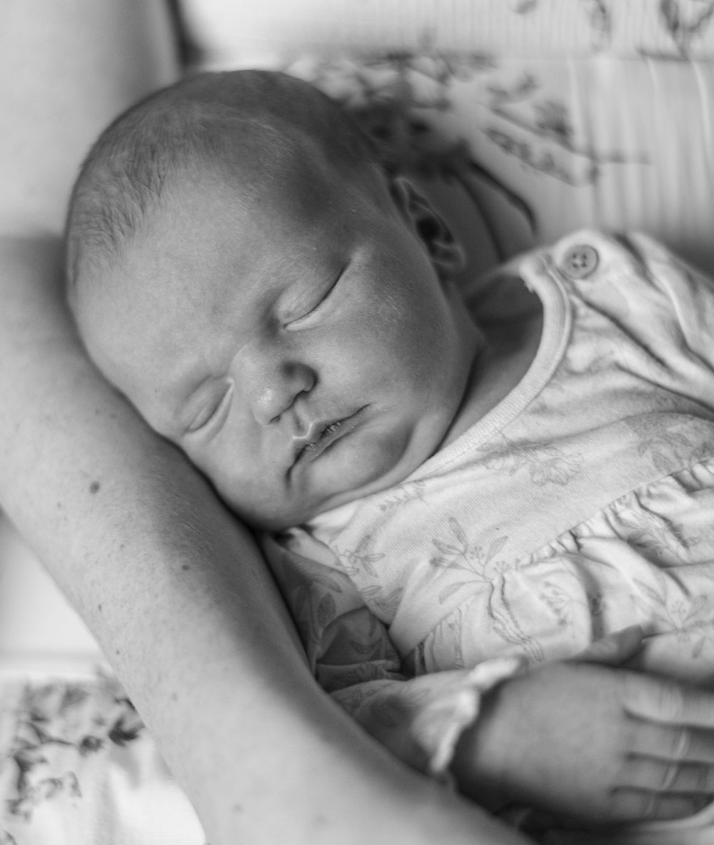 A sleeping newborn baby swaddled in white blankets shown in multiple peaceful poses.