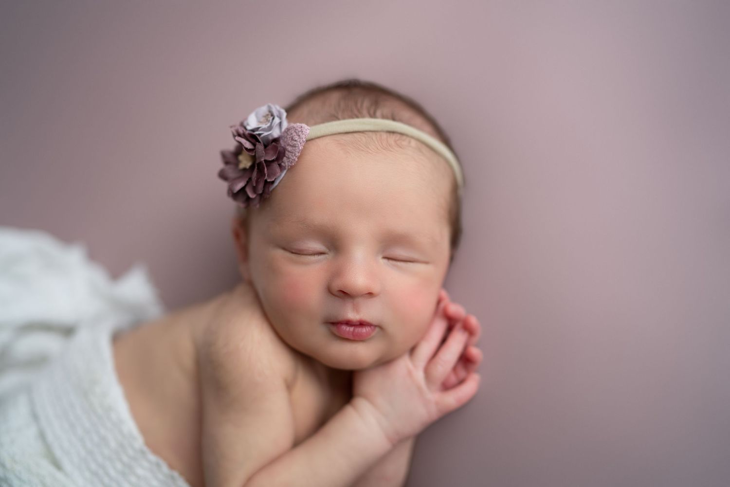 Delicate newborn photography series with soft pink tones and gentle poses.