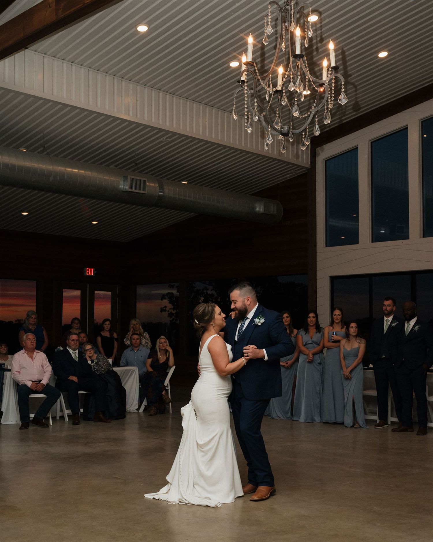 A couple shares their first dance under an elegant crystal chandelier at a wedding reception.