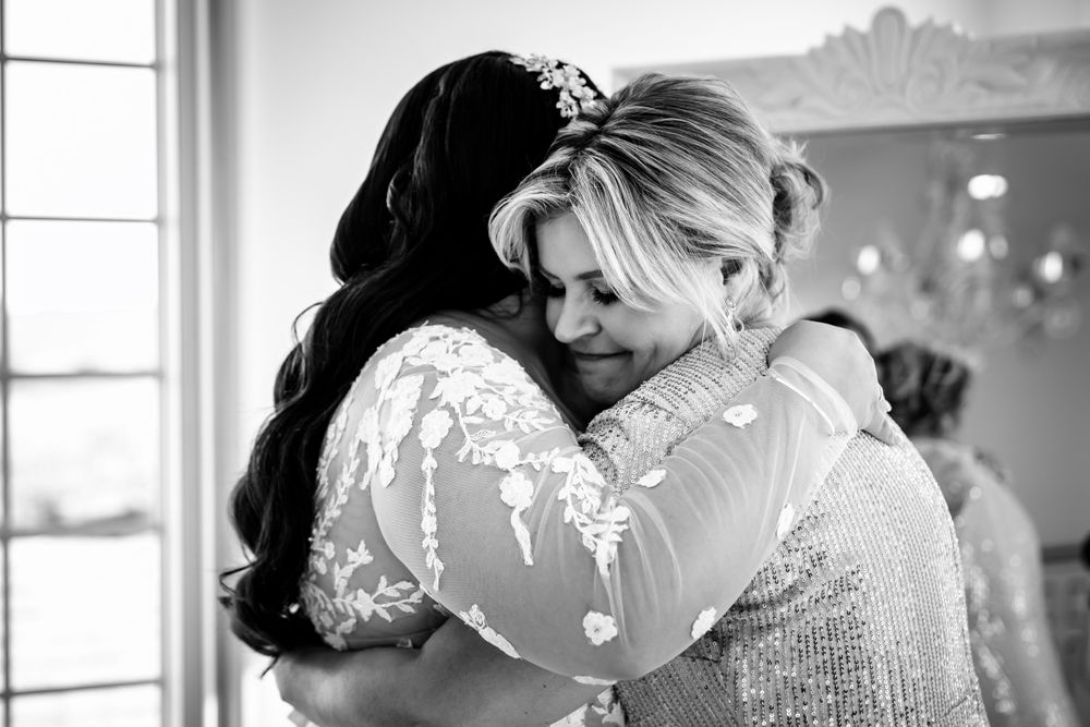 Intimate black and white photo showing emotional wedding day embraces.