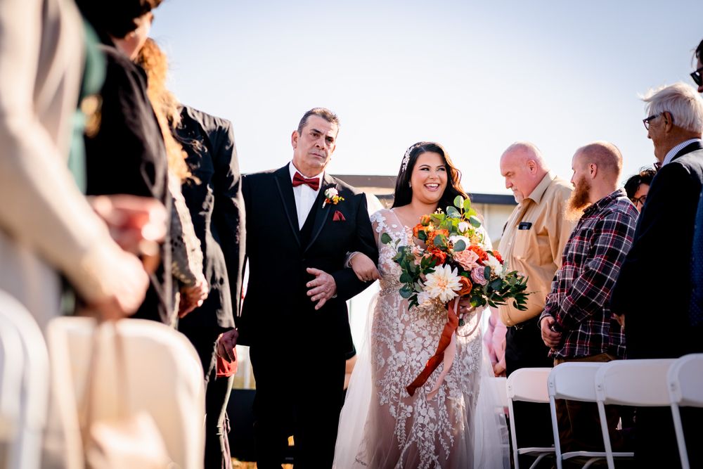 Outdoor wedding ceremony with guests gathered under bright autumn sky.
