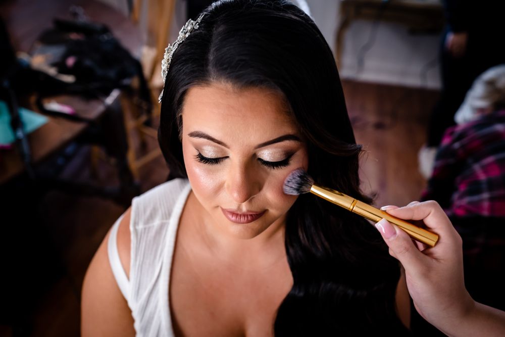 Makeup artist applies cosmetics during bridal preparation.