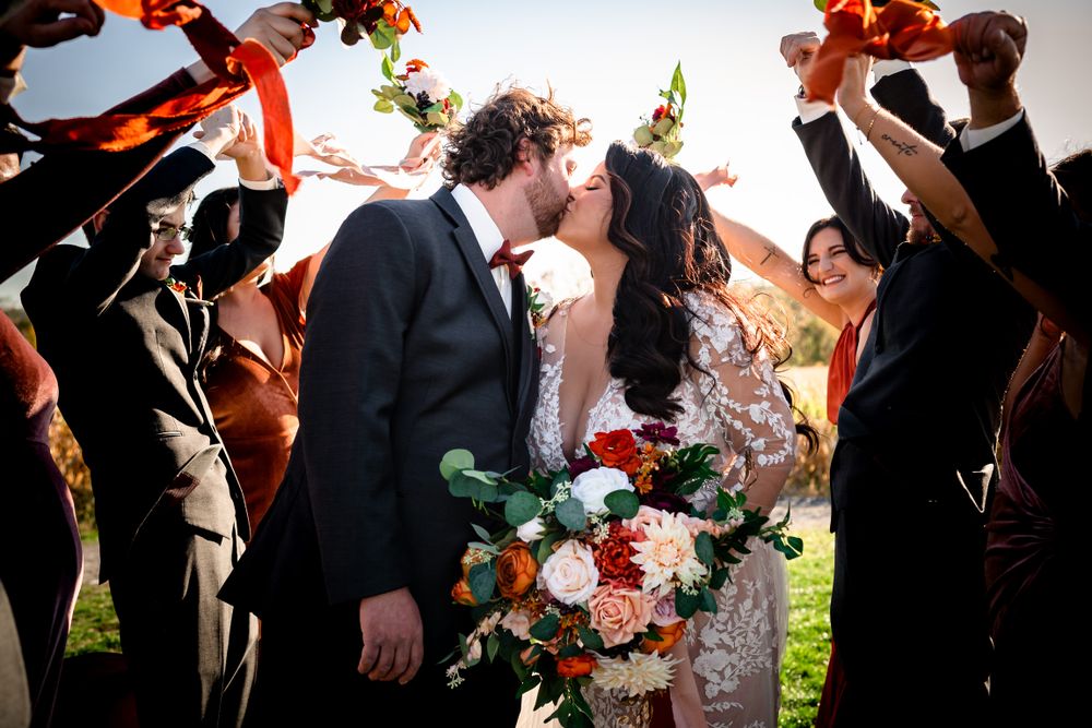 Wedding guests celebrate outdoors with colorful bouquets and floral arrangements at an autumn ceremony.