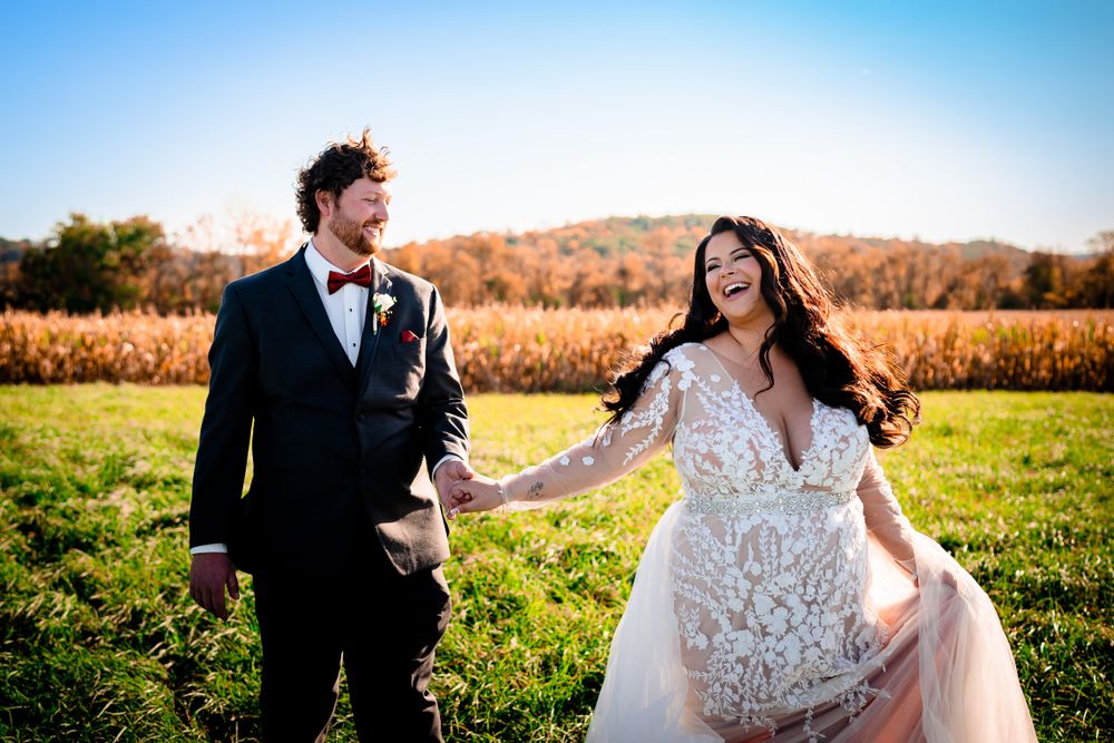Newlyweds pose together in a golden autumn field during sunset for romantic wedding photos.