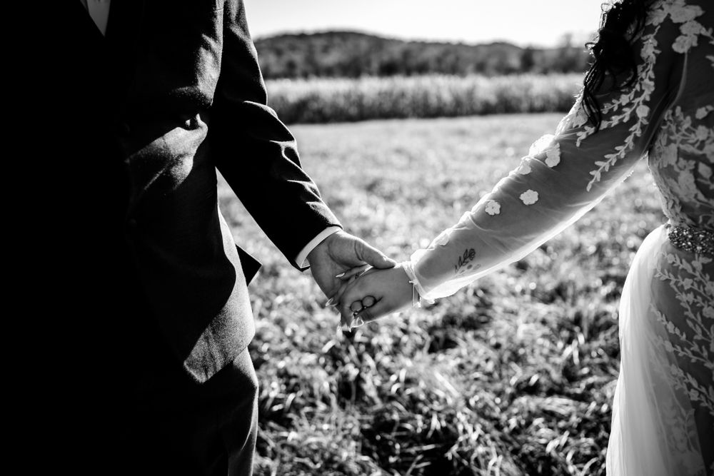 Black and white photo of a wedding couple sharing an intimate moment in a field.