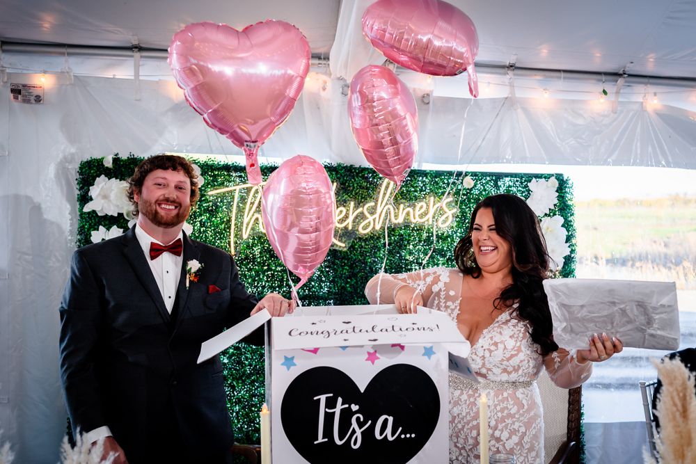 Wedding celebration with pink heart balloons and decorative greenery wall backdrop.