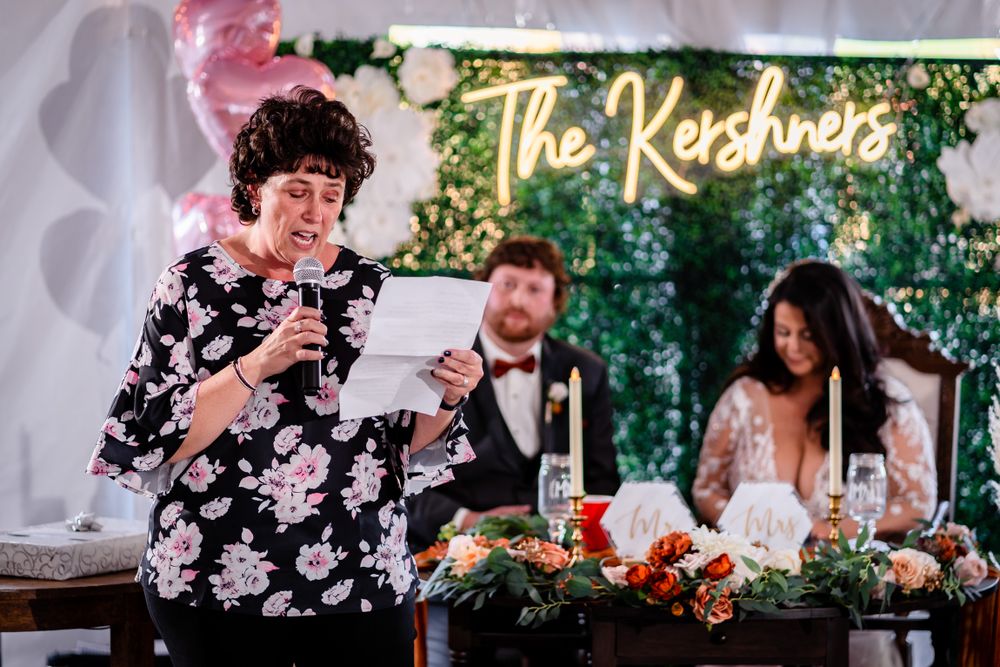 Wedding reception venue decorated with custom signage and lush greenery wall.