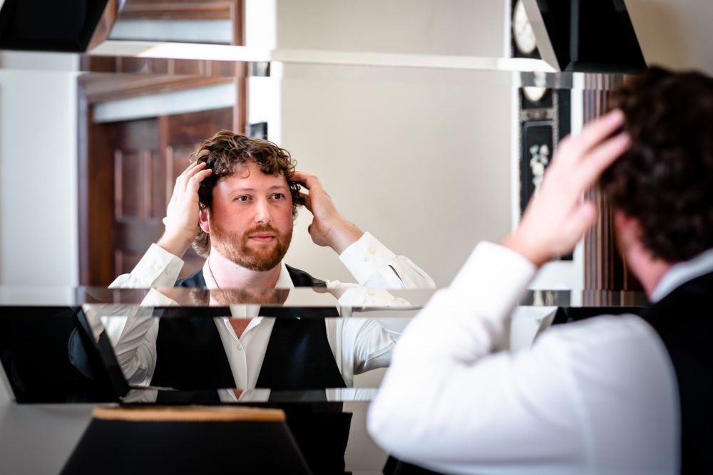 Person adjusting tie and getting ready in front of mirror.