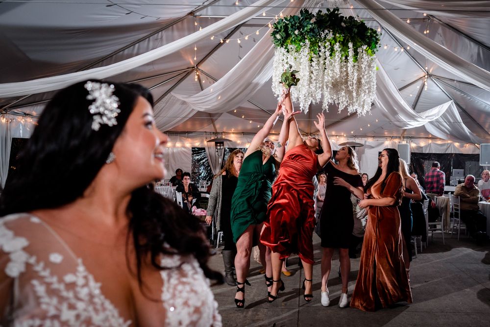 Elegant white tent wedding reception with draped fabric and hanging greenery decorations.