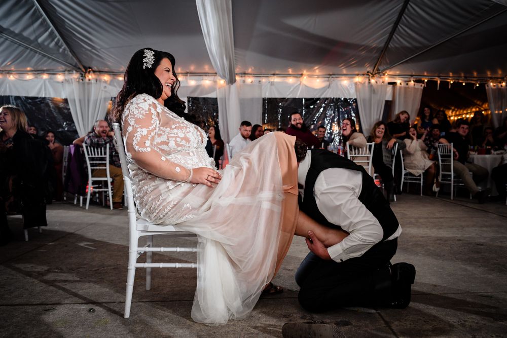 Wedding reception dance floor filled with guests celebrating under white tent and string lights.