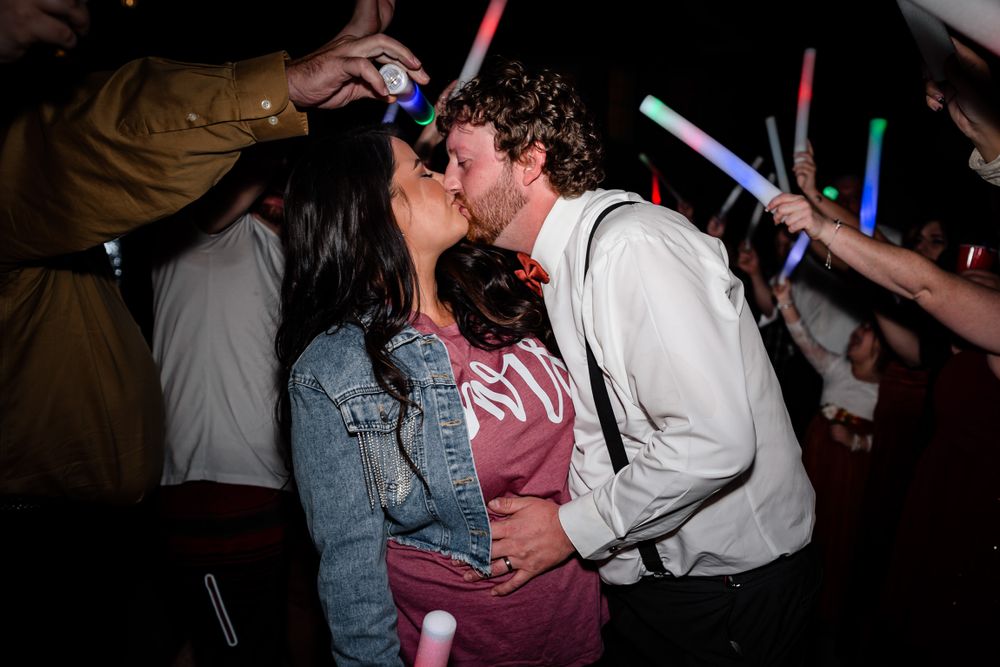 Wedding guests dancing with colorful light-up props on the dance floor at night.