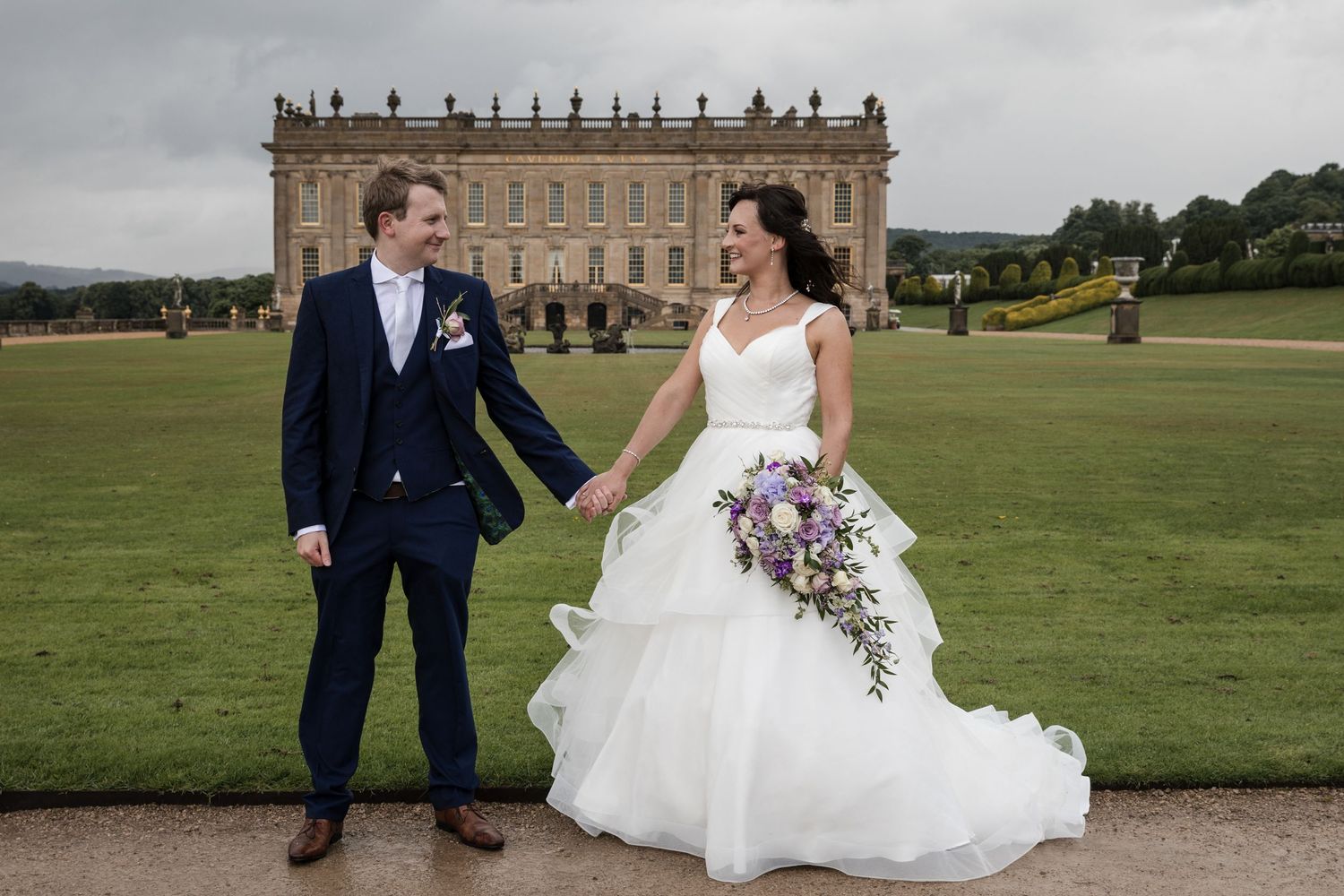 Wedding photography session on manicured grounds of historic estate with dramatic architecture.