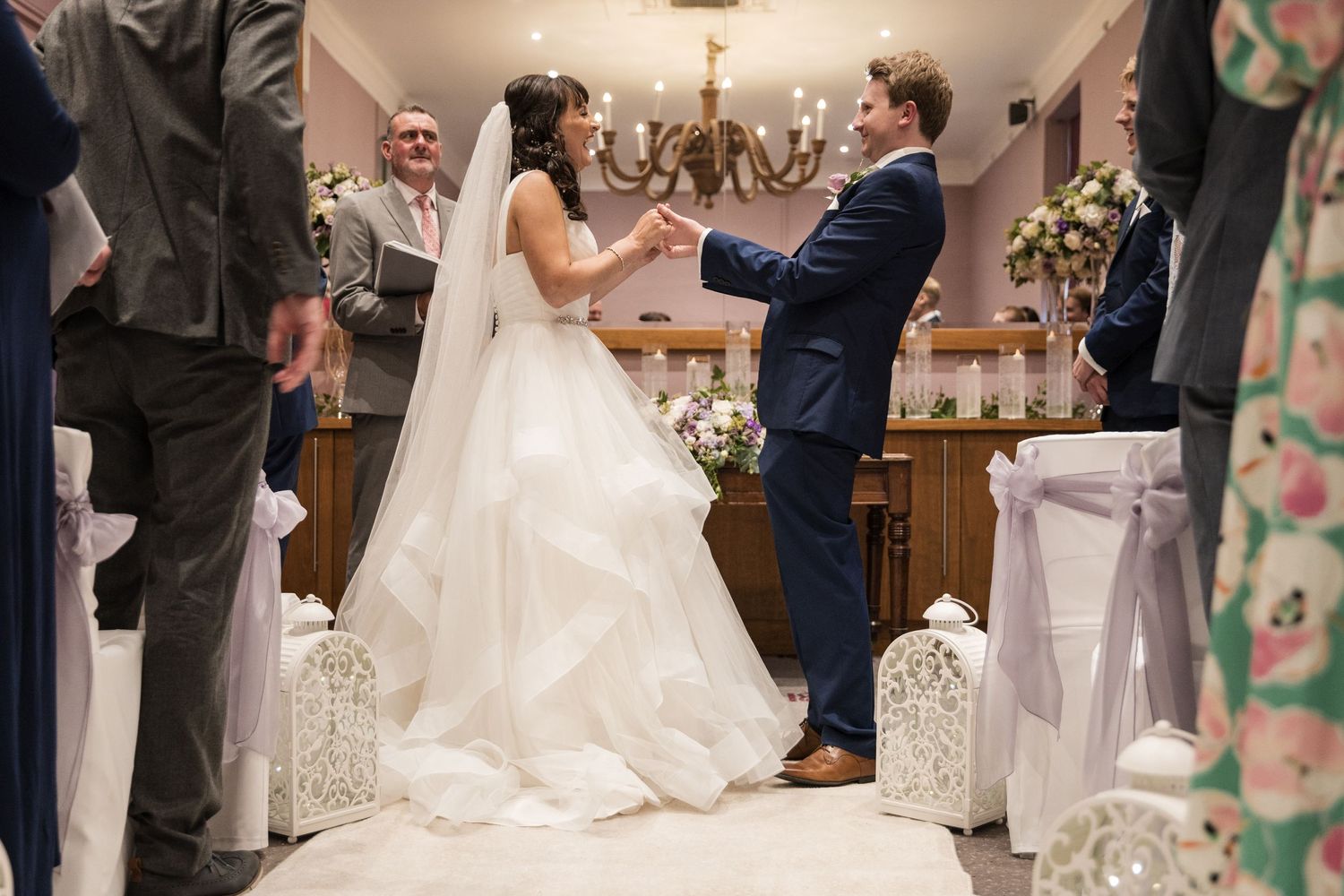 Wedding celebration in an elegant indoor venue with hanging chandeliers and white decor.