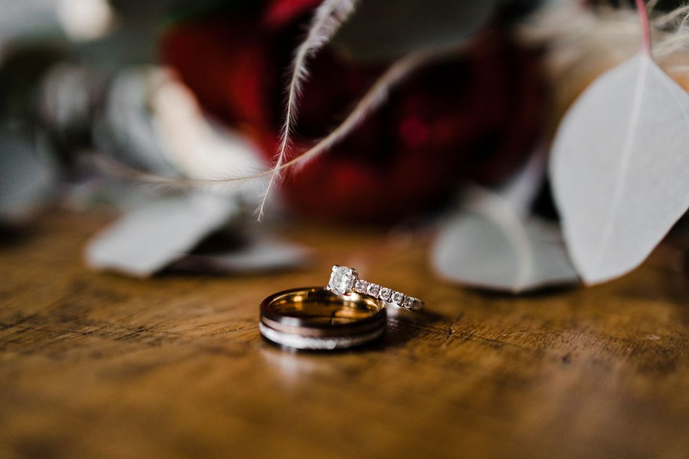 Two wedding rings arranged with delicate petals on a wooden surface.