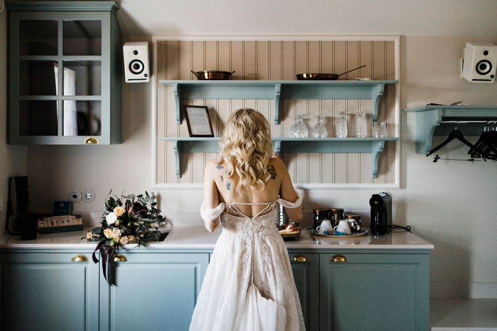 Back view of a white wedding dress in a modern blue kitchen setting.