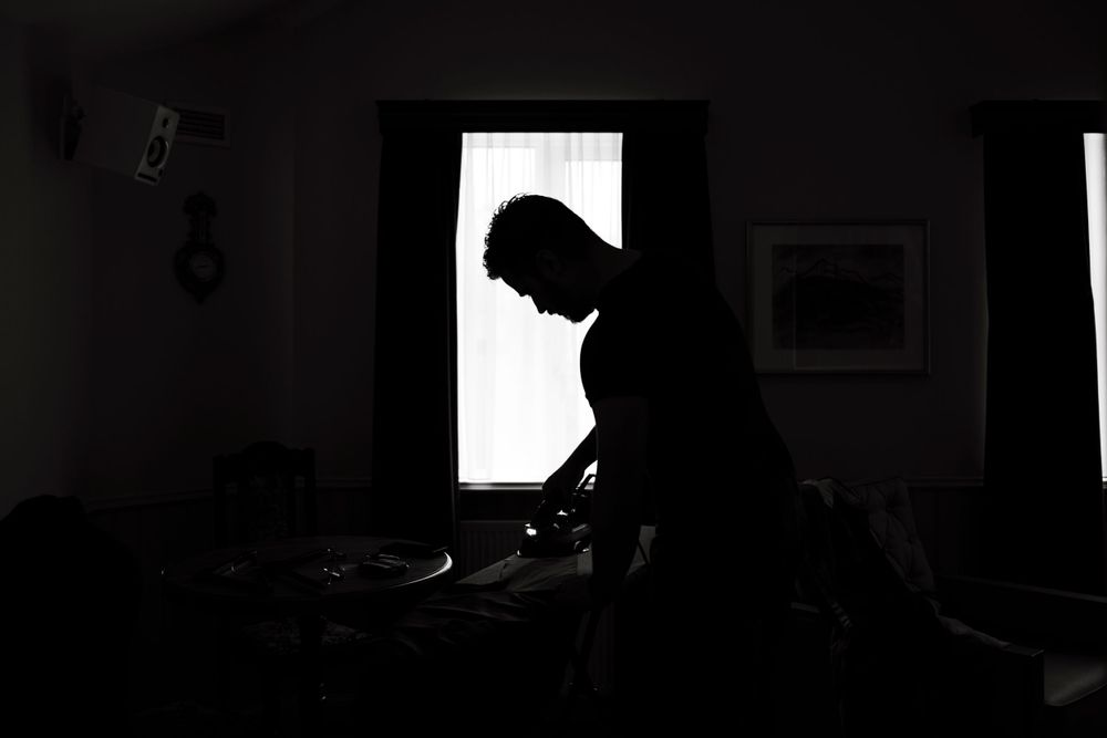 Silhouette of a person preparing near a window in dark room.